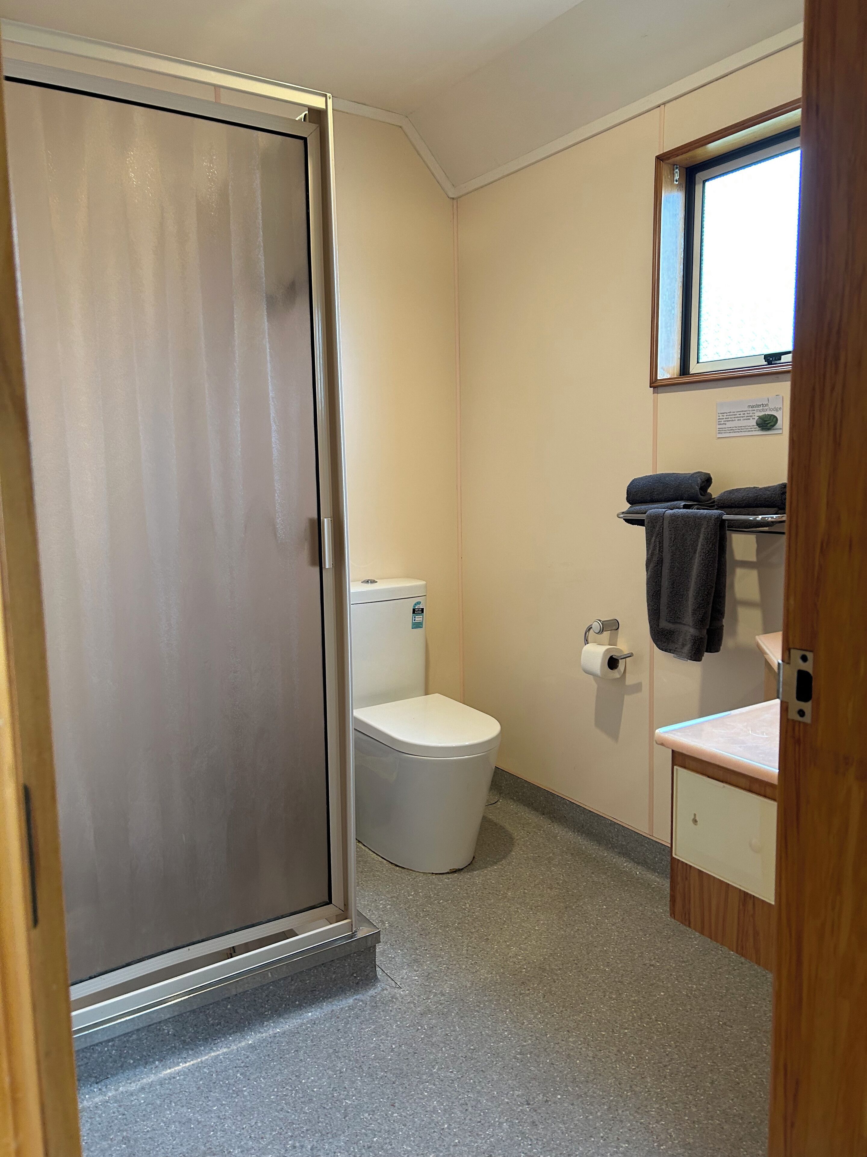 A small, compact bathroom with a toilet, a sink, and a shower area.