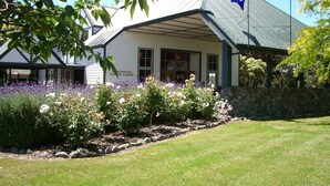 A lodge with a stone wall and a garden with lavender and white flowers.