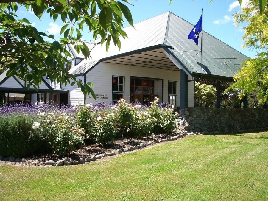 Eine Lodge mit Steinwand und Garten mit Lavendel und weißen Blüten.