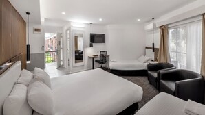 Habitación de hotel con dos camas, un escritorio, una silla, un televisor y un balcón.