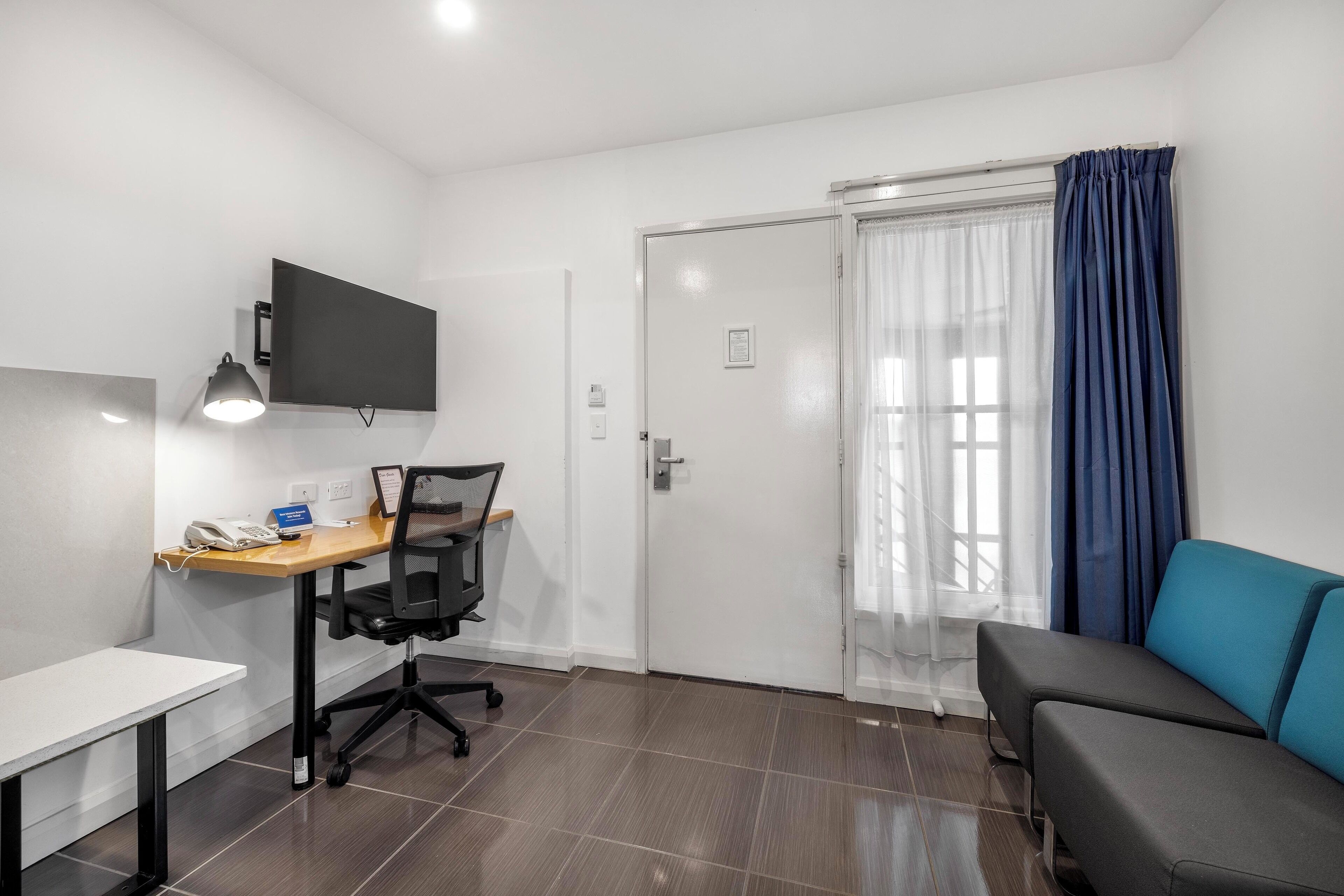 A small, modern room with a desk, chair, and a blue couch.