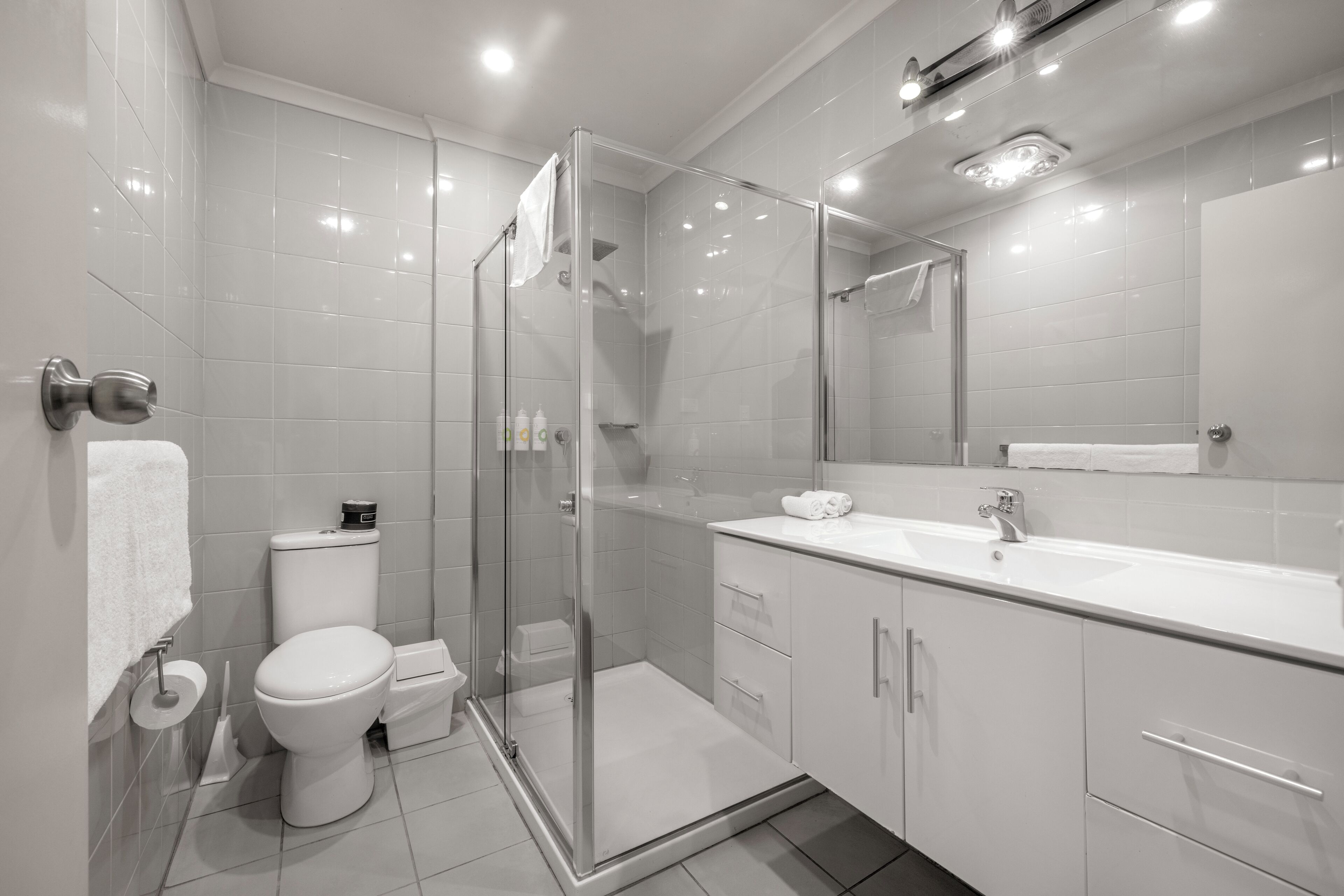 A modern bathroom with a glass shower enclosure, a white sink, and a toilet.