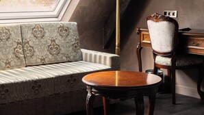 A room with a skylight, a sofa, a wooden table, a lamp, and a chair. - Hotel Cour Saint Georges by CW Hotel Collection (Ghent)