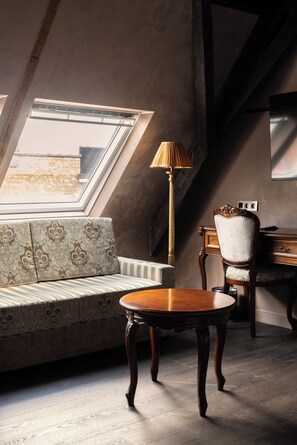 A room with a skylight, a sofa, a wooden table, a lamp, and a chair. - Hotel Cour Saint Georges by CW Hotel Collection (Ghent)