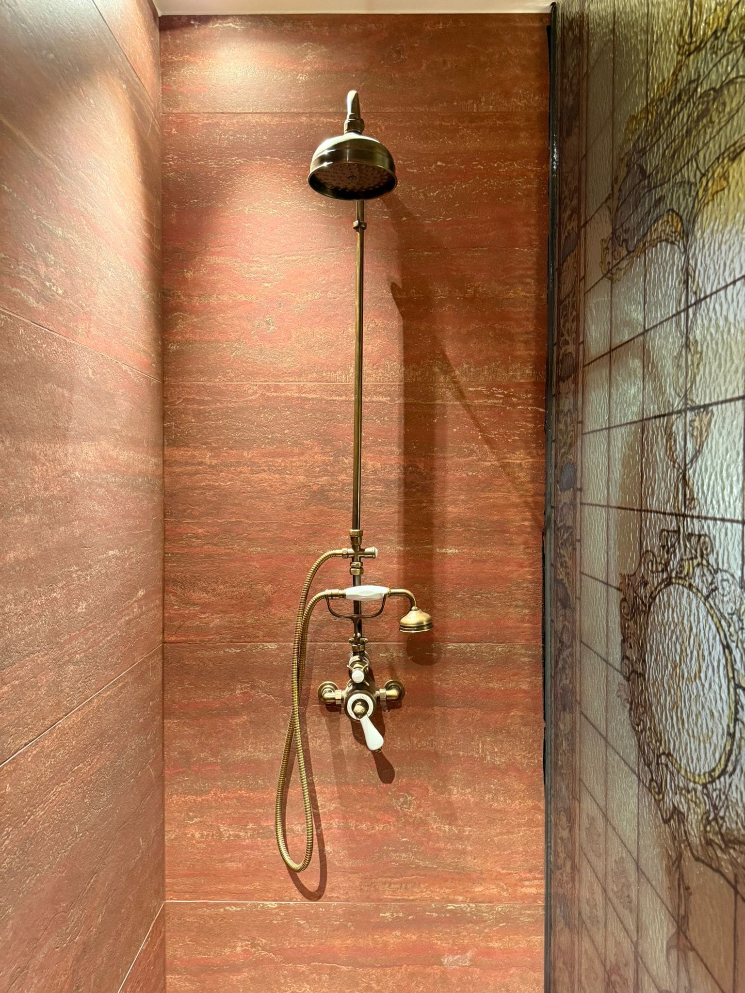 Een douche met een handdouche en een handmixer, tegen een gestructureerde wand.