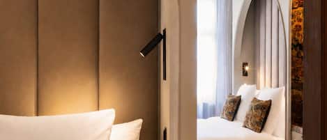 A hotel room with a large bed, a decorative pillow, an arched doorway, and a view of the room's interior.