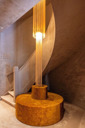 A modern interior with a unique light fixture, a spiral staircase, and a textured wall. - Hotel Cour Saint Georges by CW Hotel Collection (Ghent)