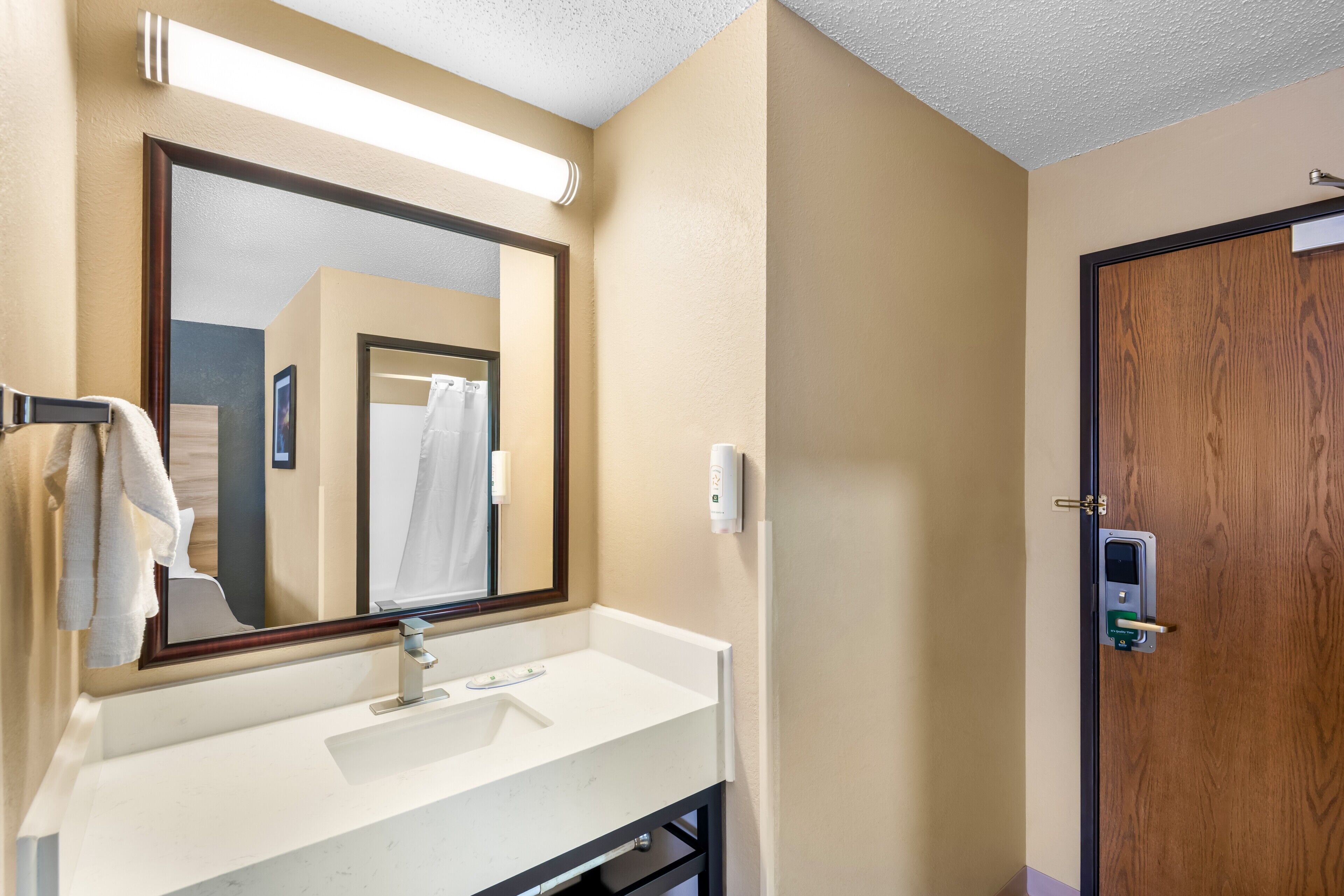 A bathroom with a white sink, a mirror, a towel rack, and a wooden door.