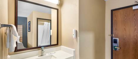 A bathroom with a white sink, a mirror, a towel rack, and a wooden door.