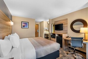 Ein Hotelzimmer mit Bett, Schreibtisch, Fernseher und Spiegel.