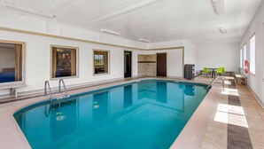 Une piscine intérieure à l’eau claire, dotée d’un sol carrelé et d’un plafond avec des spots encastrés.
