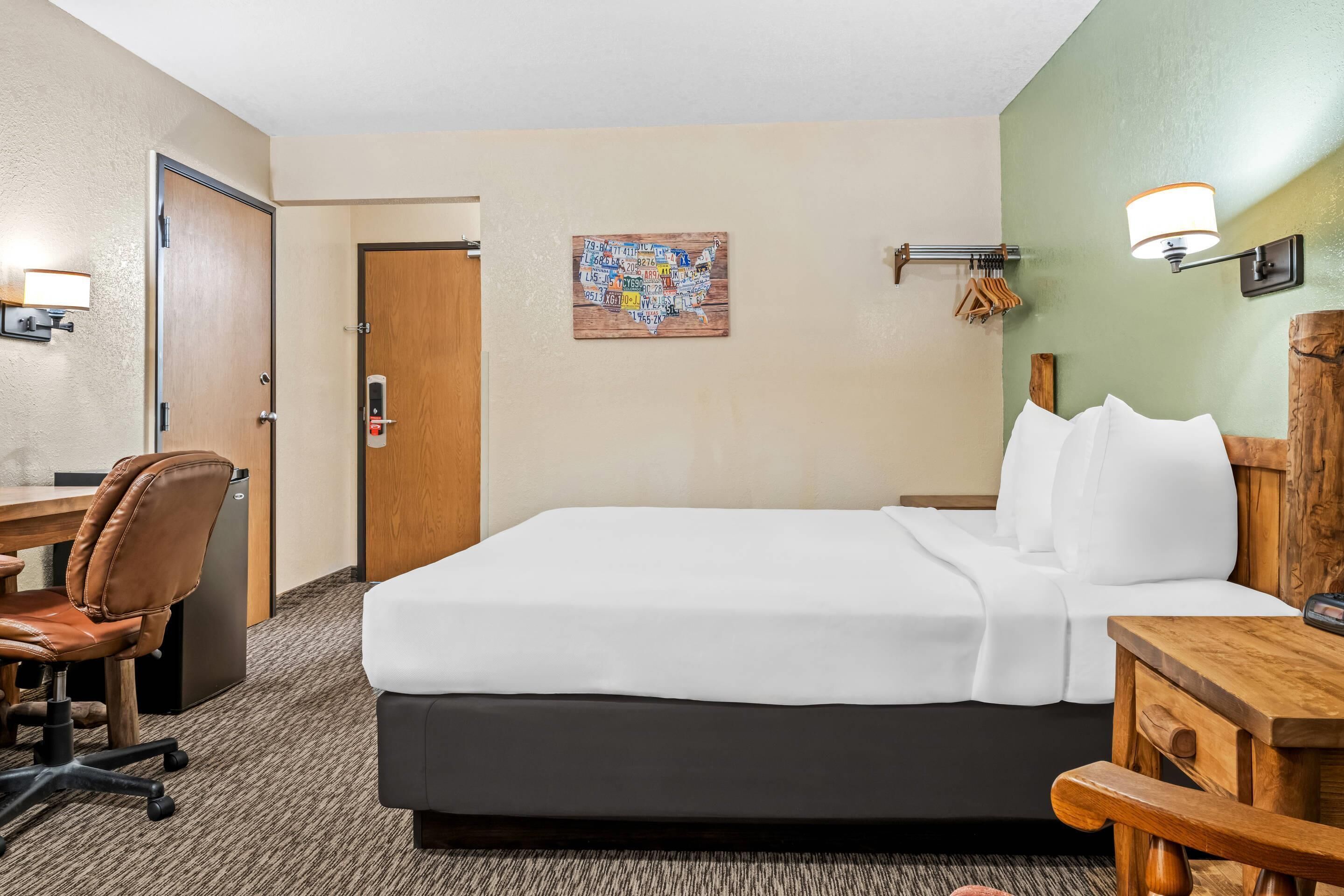 Une chambre d’hôtel équipée d’un lit, d’un bureau, d’une chaise et d’une carte géographique murale.