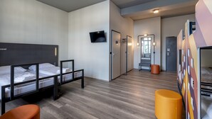 A modern hotel room with bunk beds, a flat-screen TV, a mirror, and a wooden floor. - a&o Berlin Friedrichshain (Berlin)