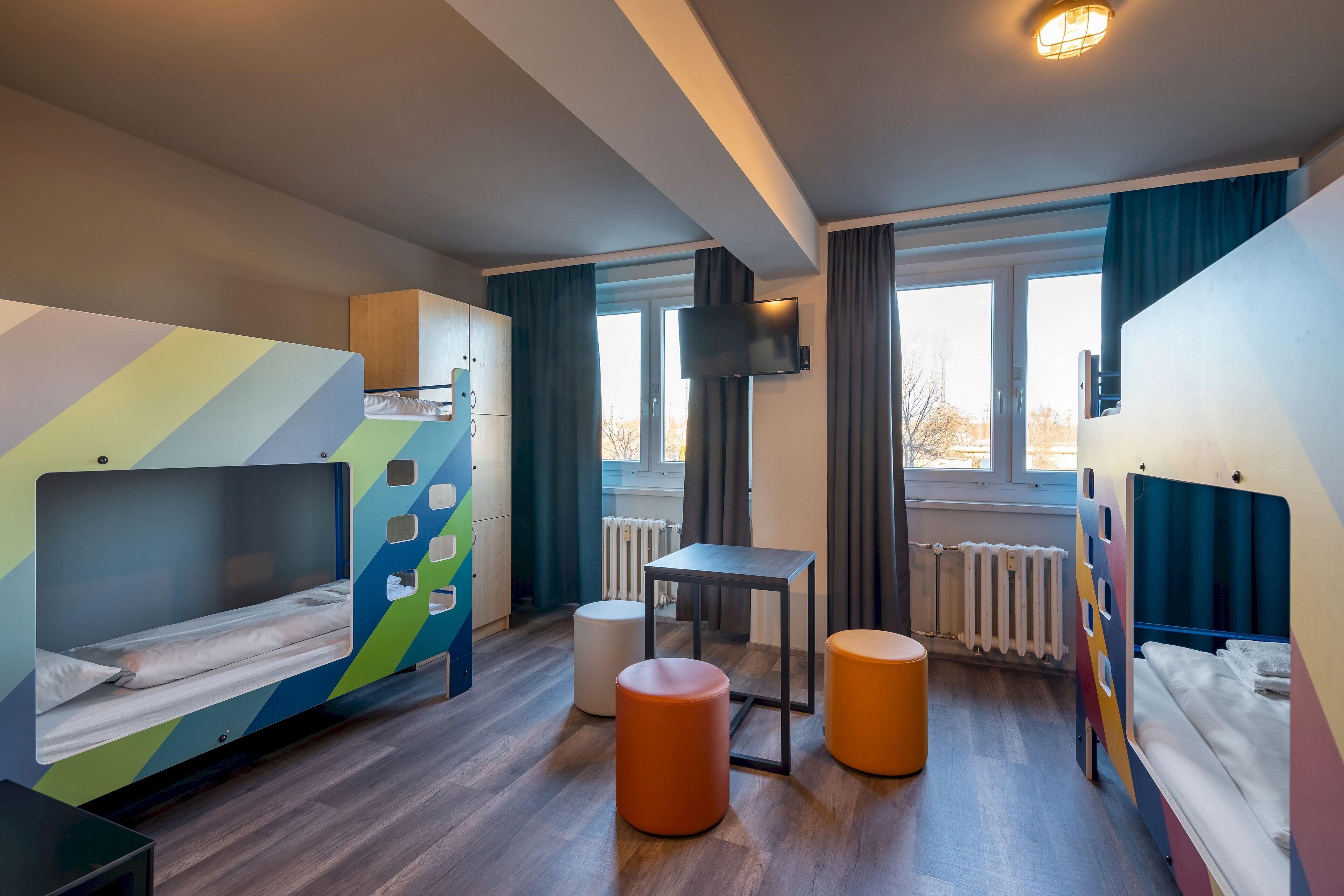 A children's room with bunk beds, a small table, and two stools.