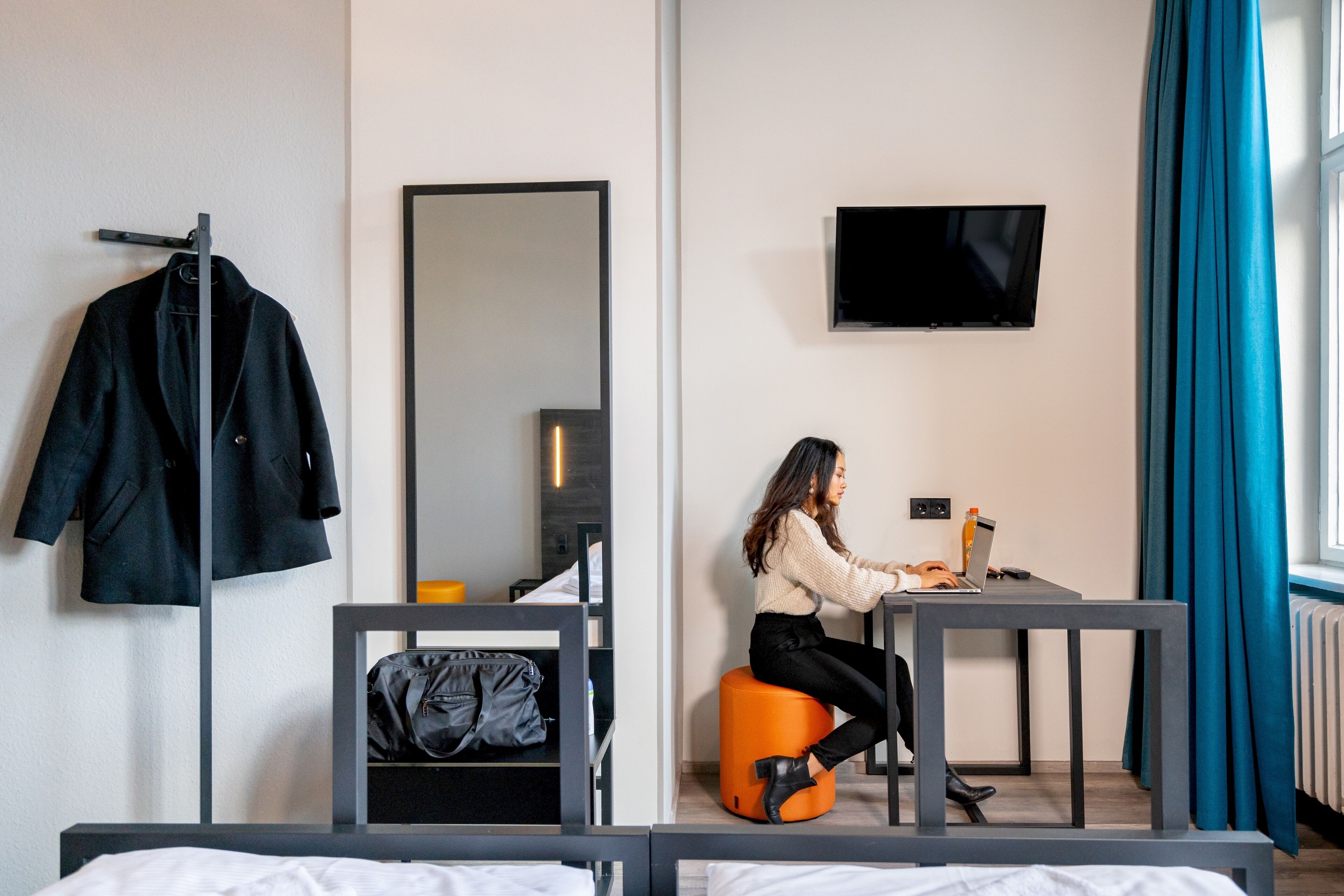 Une chambre d’hôtel avec un lit, un bureau, une chaise, une télévision et un miroir.