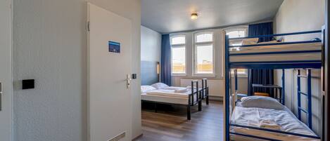 Un dormitorio con literas, una cama individual, una ventana con cortinas y una puerta con un letrero.
