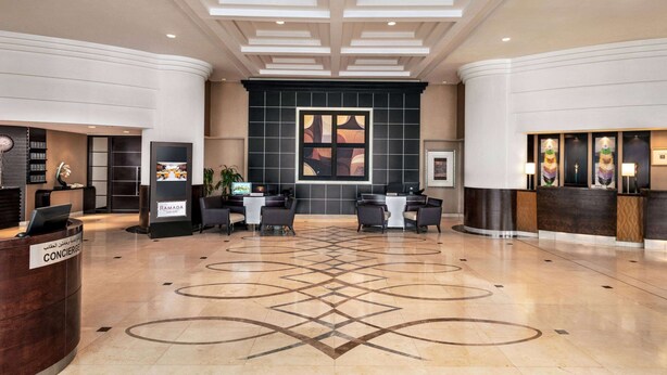 A spacious lobby with a reception desk, seating area, and a large abstract artwork on the wall.