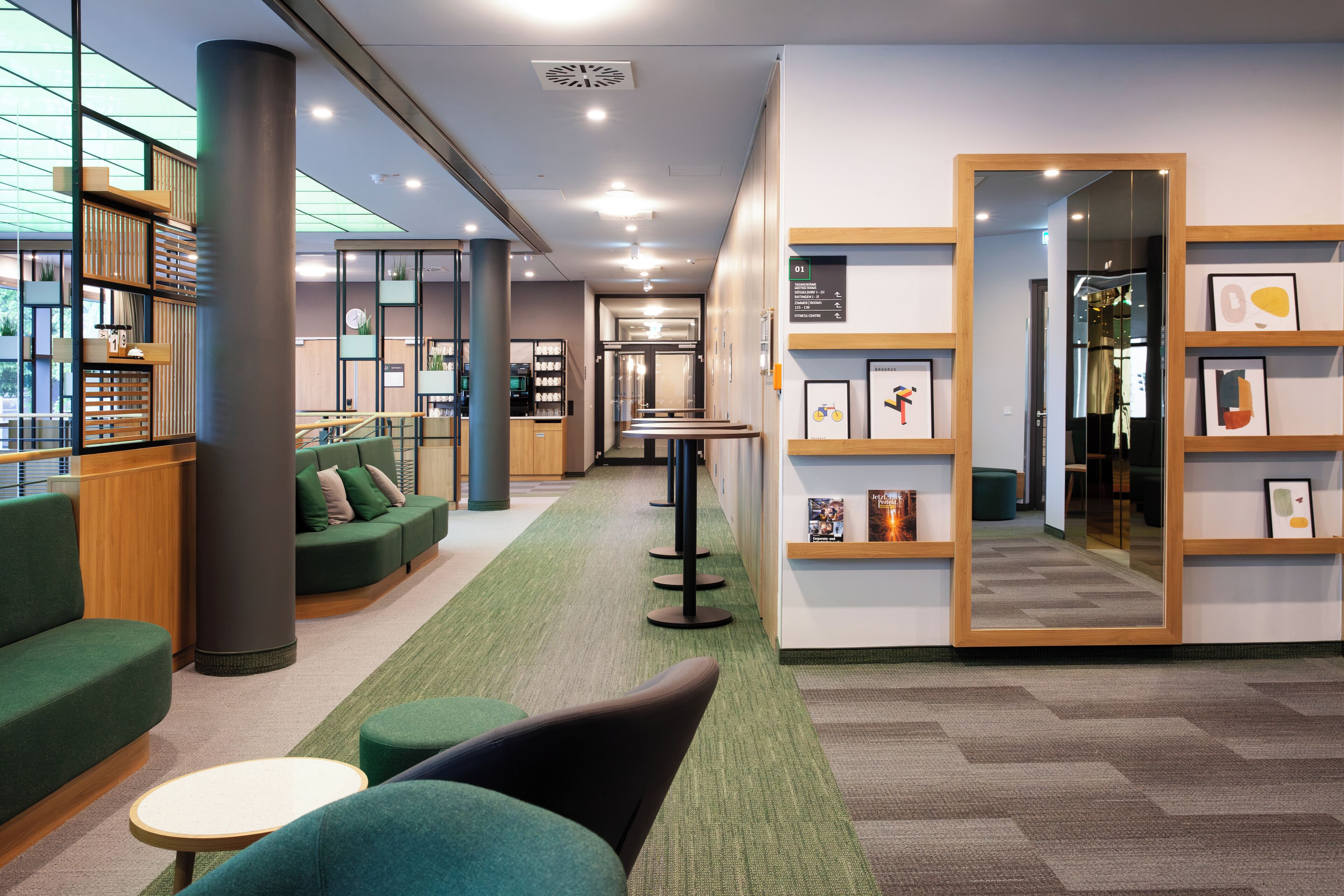 A modern lobby with green seating, a reception desk, and a wall with framed artwork.