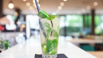 Un vaso transparente con hielo, hojas de menta y una pajita sobre una barra.