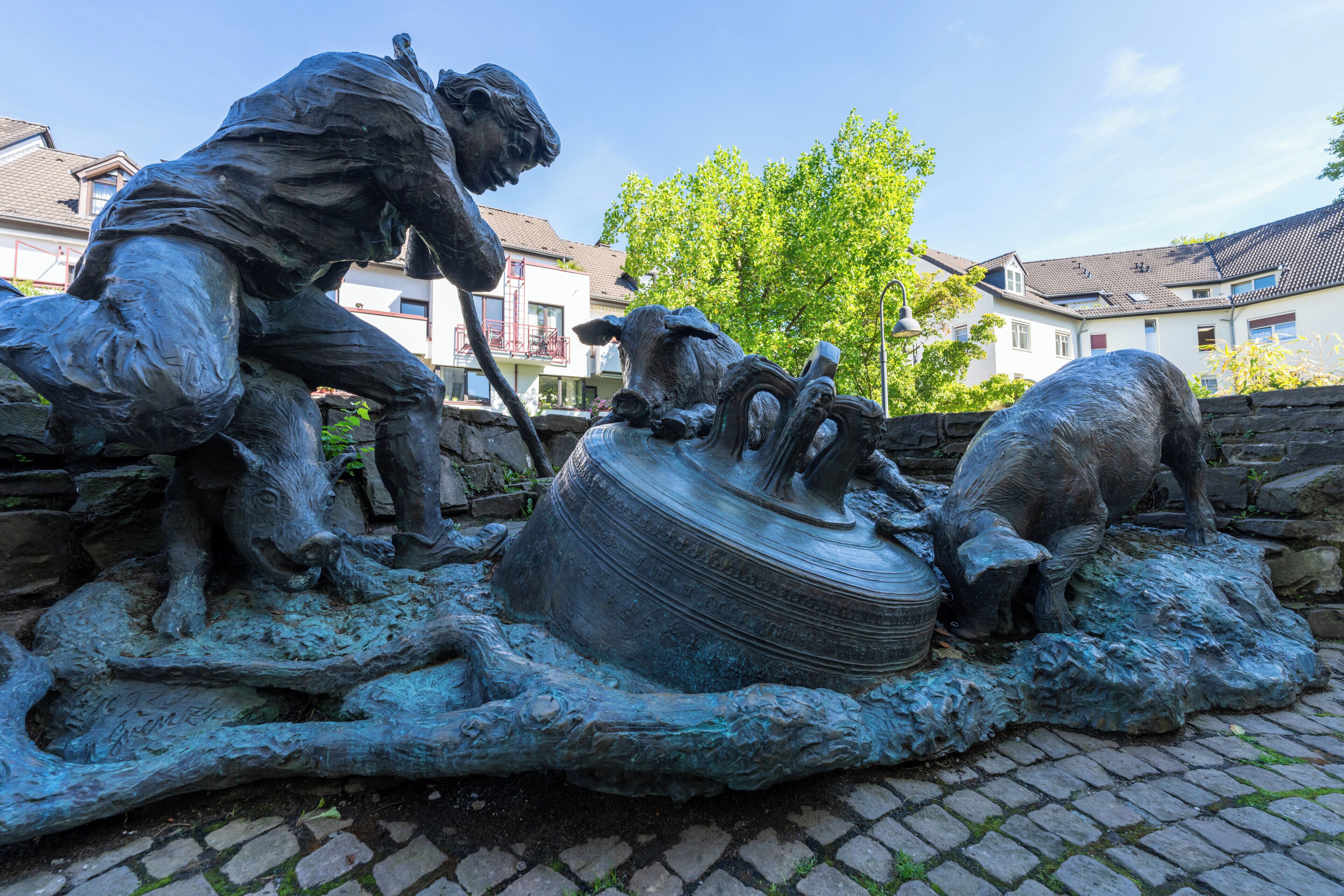 Une sculpture en bronze représentant un homme et un chien sur un chemin pavé.