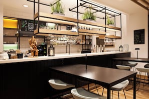 A modern bar area with a long counter, multiple seating options, and shelves with glassware and plants. - Holiday Inn Ratingen City by IHG (Ratingen)