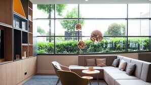 Une pièce moderne comprenant un canapé, un fauteuil, une petite table et une bibliothèque.