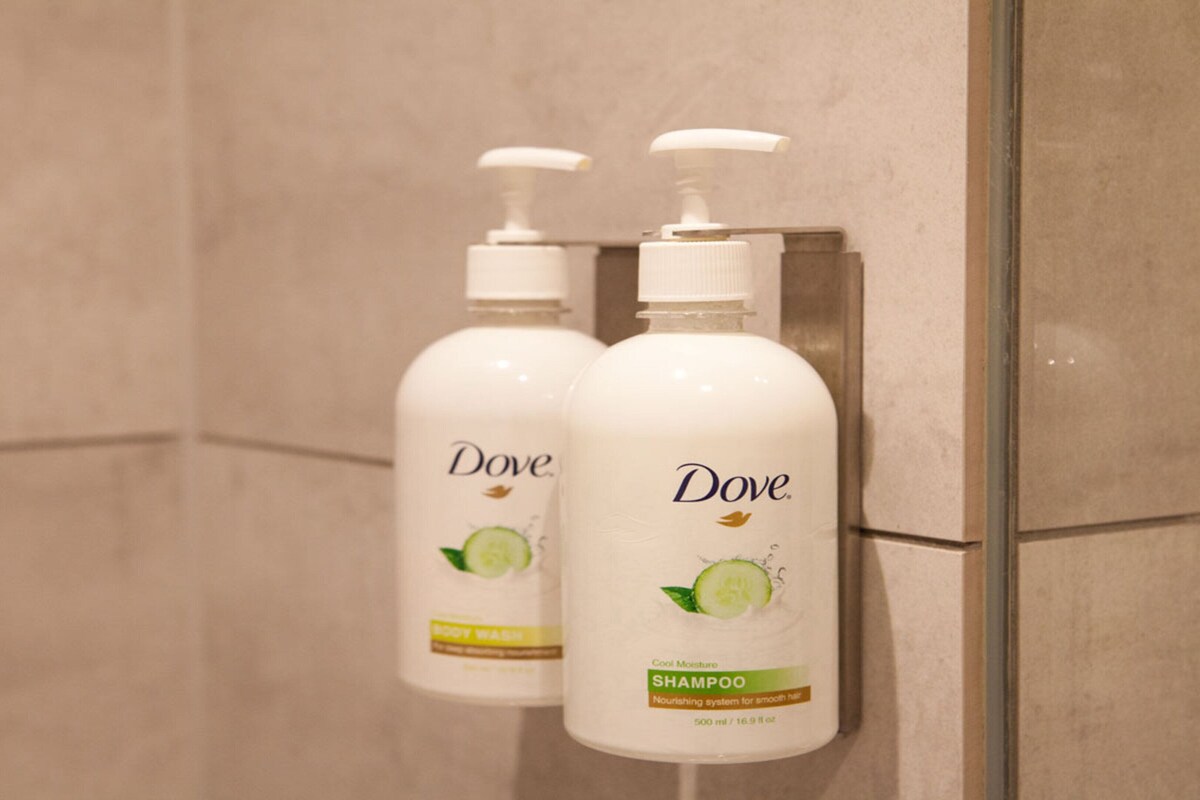 Two Dove shampoo bottles mounted on a wall in a bathroom.