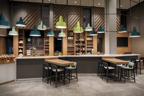 A modern bar area with a central island, multiple hanging pendant lights, and bar stools. - Holiday Inn Ratingen City by IHG (Ratingen)