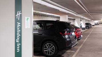 Un estacionamiento con varios automóviles, incluyendo una camioneta SUV negra y un coche rojo.