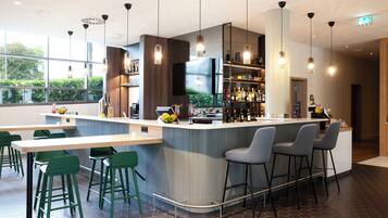 A modern bar area with a flat-screen TV, bar stools, and a variety of bottles.
