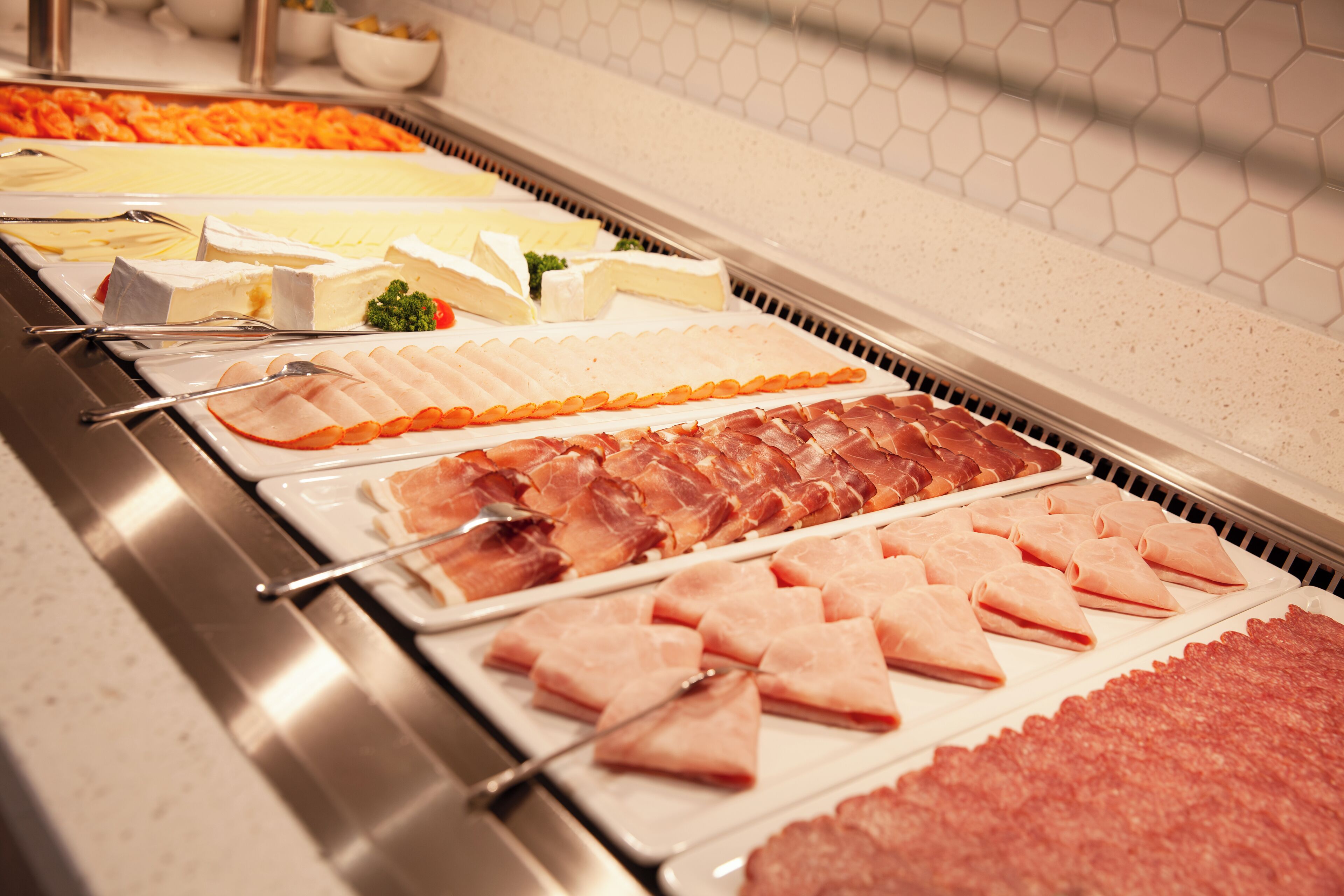 A buffet with various food items including meats and cheeses.