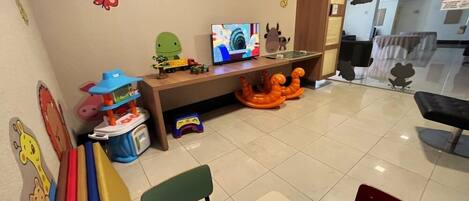 A children's play area with a TV, toys, and a small table.