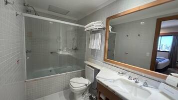A modern bathroom with a glass-enclosed shower, a toilet, a sink, and a large mirror.