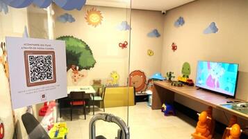 A children's play area with a QR code for family access, a television, and various toys.