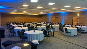 A conference room with multiple round tables and chairs, equipped with nameplates and bags.