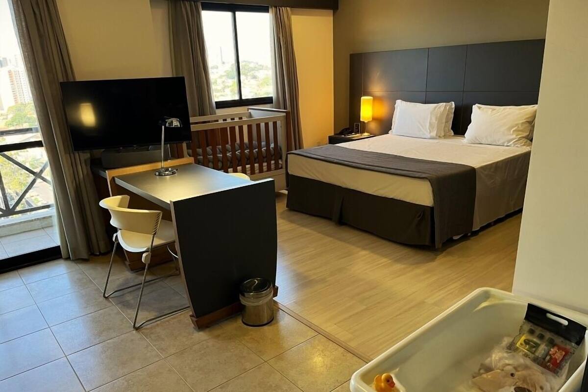 Een hotelkamer met een bed, een bureau, een televisie en een bad met een eend.