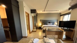 Una habitación de hotel con cama, escritorio, televisión y espejo.