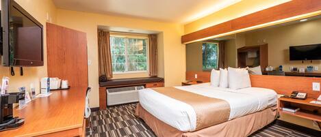 A hotel room with a large bed, a desk, a television, and a window with curtains.