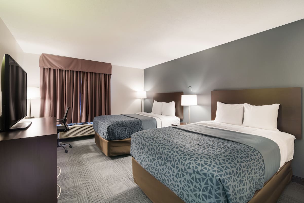 A hotel room with two beds, a desk with a computer, and a TV.