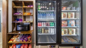 A vending machine stocked with snacks and beverages, a microwave, and a refrigerator with food items. - Econo Lodge Williston (Williston)