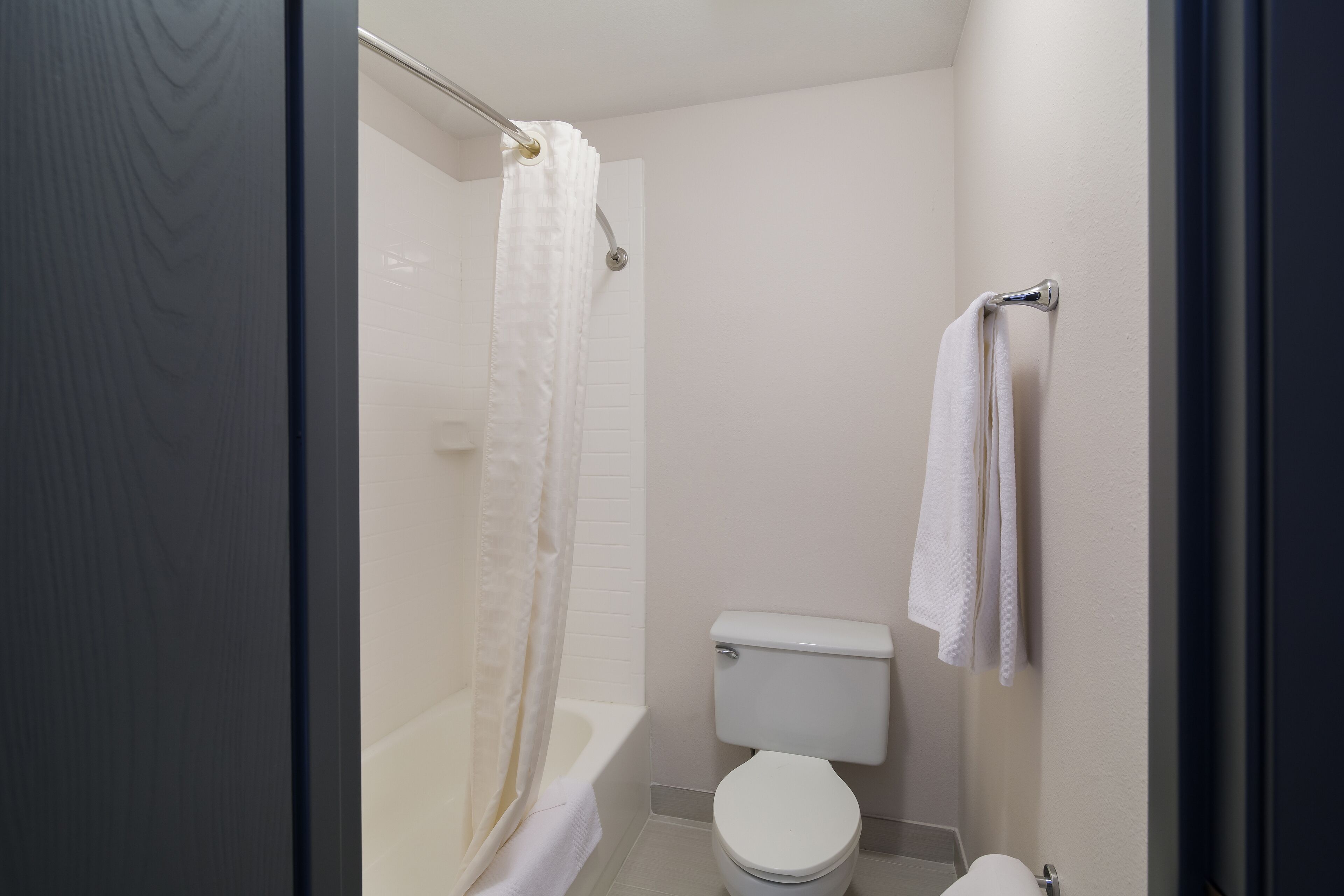 A bathroom with a bathtub, toilet, and a towel rack.