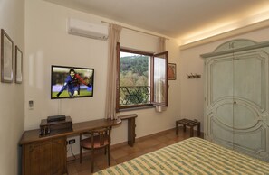 A bedroom with a bed, a desk with a chair, a television, a wardrobe, and a window with curtains. - Hotel Da Carlos (Lucca)