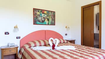 Hotellihuone, jossa on sänky, taulu seinällä, puhelin yöpöydällä ja puuovi.
