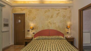 A hotel room with a large bed, two bedside lamps, a wooden door, and a radiator.