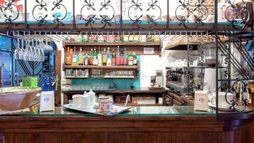 Una zona de bar con estantes llenos de botellas, vasos y una máquina de café.