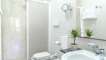Une salle de bain équipée d’une douche, de toilettes, d’un lavabo et d’une plante en pot.