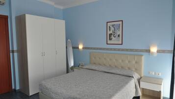A bedroom with a bed, wardrobe, bedside table, and a framed picture on the wall.