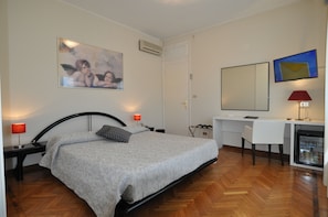 A bedroom with a bed, bedside tables, a desk, a chair, a TV, and a refrigerator. - Hotel Sole Mare (Sanremo)