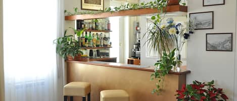 A bar area with stools, a shelf with bottles, and potted plants.
