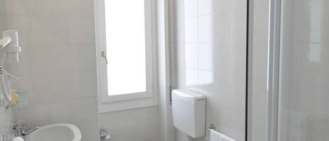 Ein modernes Badezimmer mit Toilette, Bidet, Waschbecken und Duschkabine aus Glas.